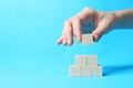 Woman building pyramid of cubes on light blue background, closeup with space for text. Idea concept Royalty Free Stock Photo