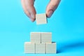 Woman building pyramid of cubes on light blue background, closeup with space for text. Idea concept Royalty Free Stock Photo