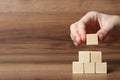 Woman building pyramid of cubes on wooden background, closeup with space for text. Idea concept Royalty Free Stock Photo