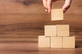 Woman building pyramid of cubes on wooden background, closeup with space for text. Idea concept Royalty Free Stock Photo