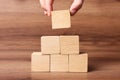 Woman building pyramid of cubes on wooden background, closeup with space for text. Idea concept Royalty Free Stock Photo