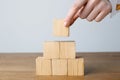 Woman building pyramid of cubes on wooden table against light background, closeup. Space for text Royalty Free Stock Photo