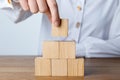 Woman building pyramid of cubes on wooden table, closeup. Space for text Royalty Free Stock Photo