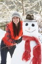 Woman Building Snowman In Garden