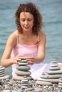 Woman builds stone stacks on pebble beach Royalty Free Stock Photo