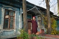 Woman in a burgundy coat and beret is waiting standing on the porch