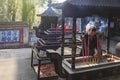 Dujiangyan, China - December 12, 2018: Woman burning incense in a Buddhist temple in the Dujiangyan water reservoir area close to