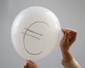 A woman bursts with a needle a balloon with the inscription euro.