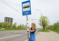 Woman at bus stop with pole tags driving schedules