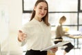 Woman in business clothes stands near white board smiling