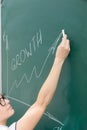woman business coach in a white blouse and glasses at the chalkboard in the office draws a profit graph. close-up