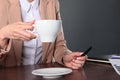 A woman in a business suit holds a white Cup of coffee in her hand. Unrecognizable photo. Copy of the space