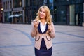 Woman in business suit uses speakerphone while standing in front of an office building. Royalty Free Stock Photo