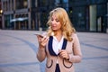 Business woman uses speakerphone while talking on phone near building of business center. Royalty Free Stock Photo