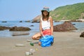 Woman busy collecting rubbish, holds garbage bag