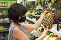 Woman buyer protective medical mask chooses a pineapple