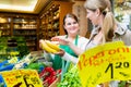 Woman buying banana in fruit grocer store