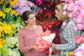 Woman buying flowers in garden center carry shopping basket smiling Royalty Free Stock Photo