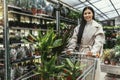 Woman buying flowers pushing shopping cart in garden center Royalty Free Stock Photo