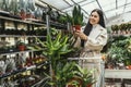 Woman buying flowers pushing shopping cart in garden center Royalty Free Stock Photo