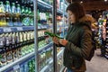 MINSK, BELARUS - October 4, 2019: Woman buys alcohol in grocery store. Young woman reading ingredients, declaration or expiration