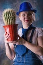 Woman with a cactus in her hand. The thorny plant is the symbol of the year. Long dangerous needles. Flower pot Royalty Free Stock Photo