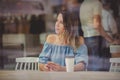 Woman in a cafe and drinking coffee and use mobile phone while sitting by the window Royalty Free Stock Photo