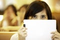 Woman looking at the camera from behind the computer tablet