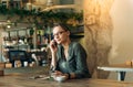 Woman at cafe making a phone call and using laptop computer. Beautiful young woman sitting at coffee shop working on laptop and Royalty Free Stock Photo