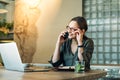 Woman at cafe making a phone call and using laptop computer. Beautiful young woman sitting at coffee shop working on laptop and Royalty Free Stock Photo