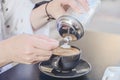 A woman in a cafe pours sugar into a cup of coffee. adding white sugar to the coffee