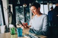 A woman in a cafe reads a message on her phone