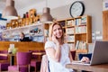 Woman in cafe, talking on phone working on notebook Royalty Free Stock Photo