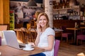 Woman in cafe, talking on phone, working on notebook Royalty Free Stock Photo