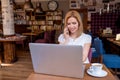 Woman in cafe, talking on phone, working on notebook Royalty Free Stock Photo