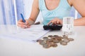 Woman calculating invoice by coins and thermostat at desk