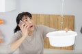 Woman calling and collecting water in bucket from ceiling Royalty Free Stock Photo