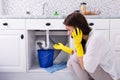 Woman Calling Plumber In Front Of Water Leaking From Pipe Royalty Free Stock Photo