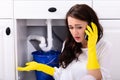 Woman Calling Plumber In Front Of Water Leaking From Pipe