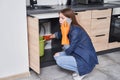 Woman calling plumber while sitting in front of water leaking Royalty Free Stock Photo