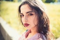 Woman on calm face with make up, nature on background, defocused. Girl with long hair wears unbuttoned shirt on sunny