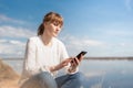 Woman with calm look sitting looking at phone outdoors