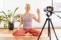 Woman with camera streaming for yoga blog at home Royalty Free Stock Photo