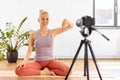 Woman with camera streaming for yoga blog at home Royalty Free Stock Photo