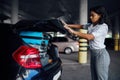 Woman can`t close trunk with suitcases, parking