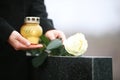Woman with candle and rose near granite tombstone outdoors, closeup. Funeral ceremony Royalty Free Stock Photo