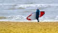 A woman with a cap on the head, practicing stand up paddle, on the North Sea in the Netherlands with large waves and strong winds