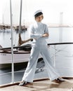 Woman in a captains hat standing on top of a sailboat