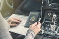 Woman in the car with laptop and american passport. Travel concept. Royalty Free Stock Photo