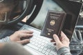 Woman in the car with laptop and germany passport. Travel concept. Royalty Free Stock Photo